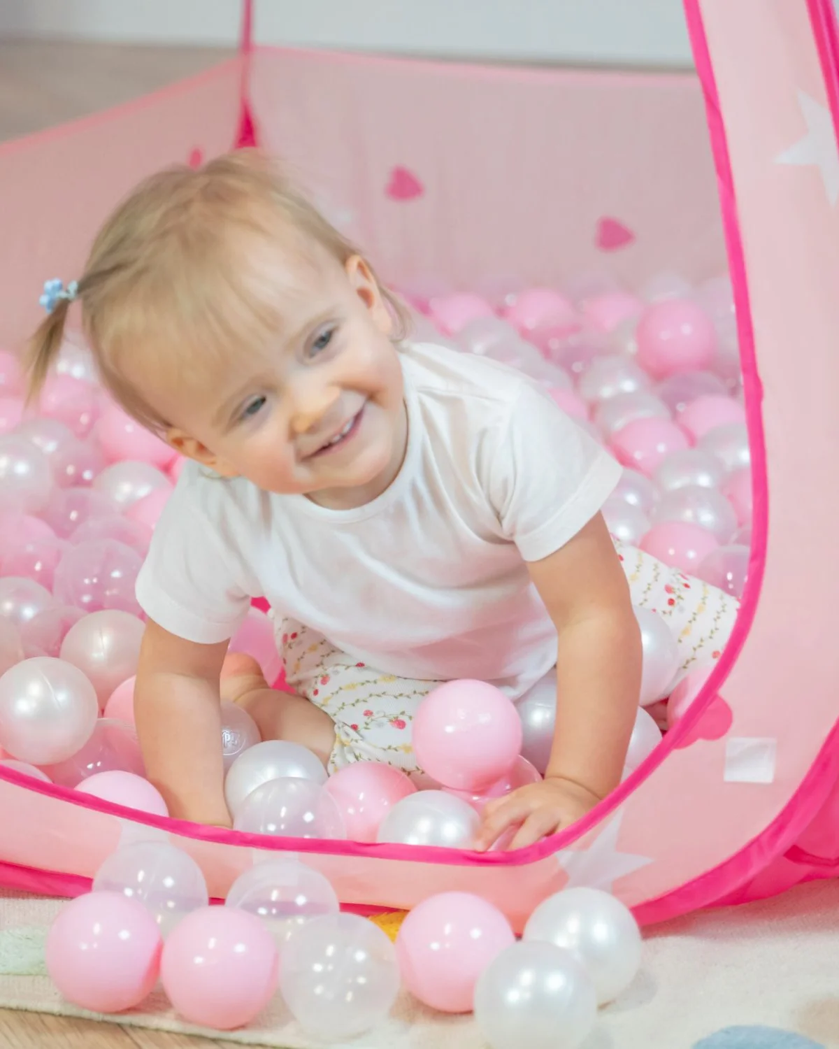 Enfant dans une tente de jeu rose avec des balles