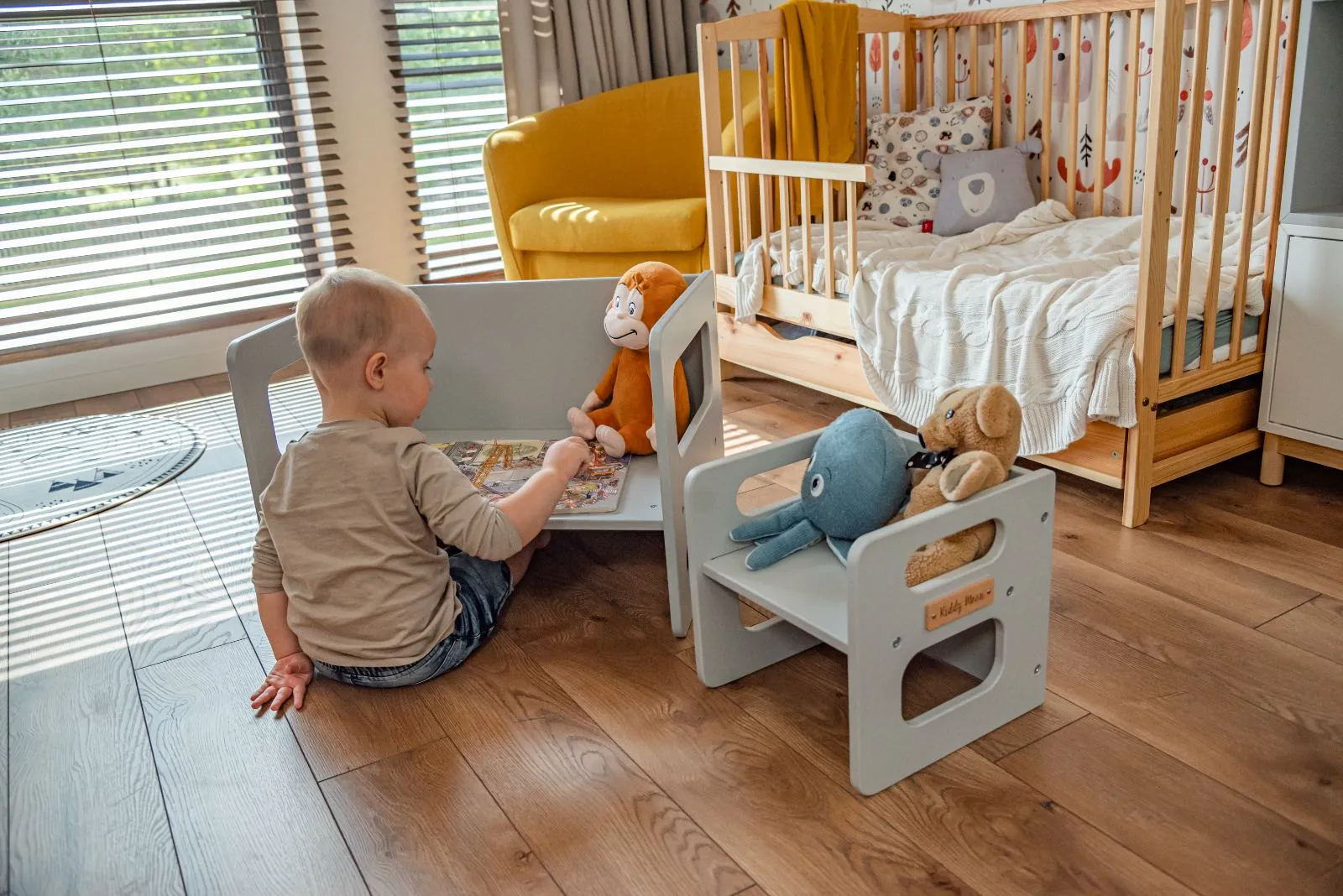Petit enfant en train de lire un livre sur la banquette grise KiddyMoon
